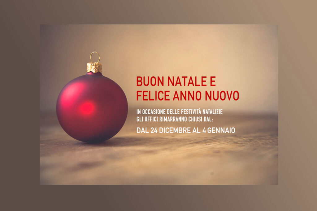 Buon Natale e Felice Anno Nuovo: uffici chiusi dal 24 dicembre al 1 gennaio, pallina di Natale rossa su superficie in legno.
